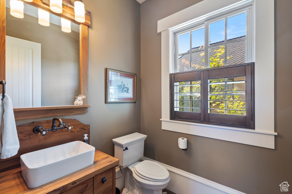 Bathroom with a wealth of natural light, toilet, vanity, and wood-type flooring