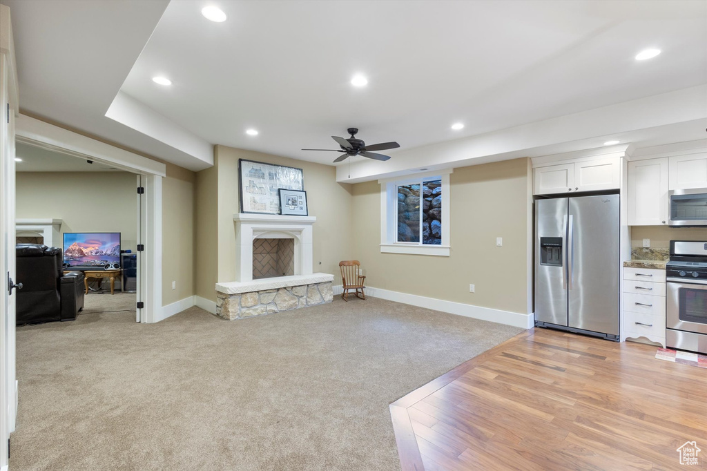 Carpeted living room with ceiling fan and a fireplace