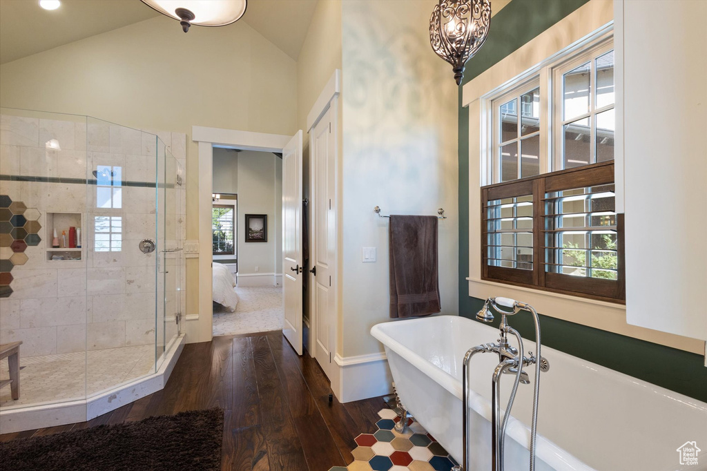 Bathroom featuring hardwood / wood-style flooring, high vaulted ceiling, and shower with separate bathtub