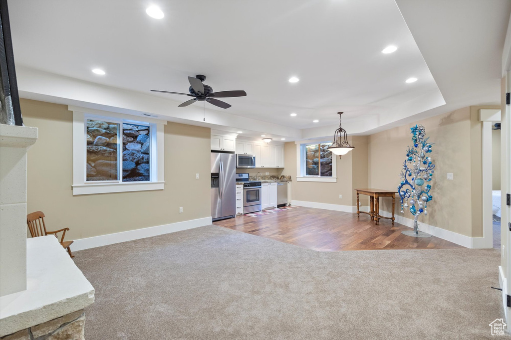 Interior space with ceiling fan, a raised ceiling, and light colored carpet