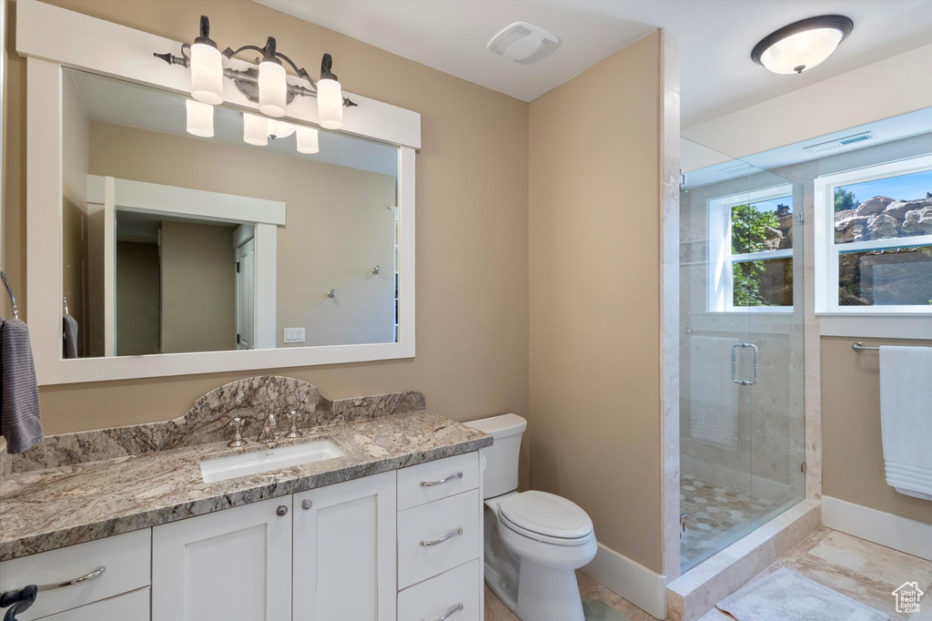 Bathroom with tile patterned flooring, a shower with shower door, vanity, and toilet