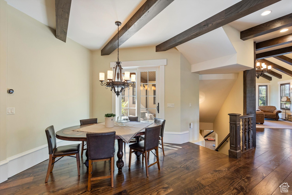 Dining area with vaulted ceiling with beams, a notable chandelier, and dark wood-type flooring