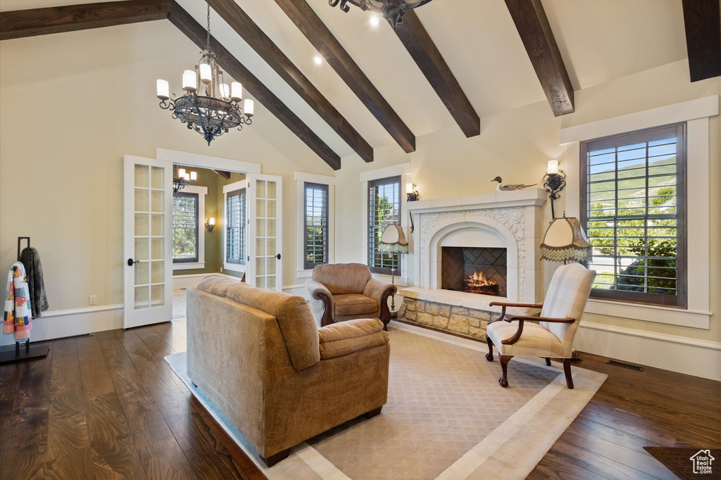 Living room with beam ceiling, hardwood / wood-style flooring, an inviting chandelier, and a premium fireplace