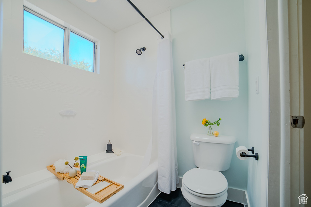 Bathroom featuring shower / bath combination with curtain, toilet, and tile patterned floors