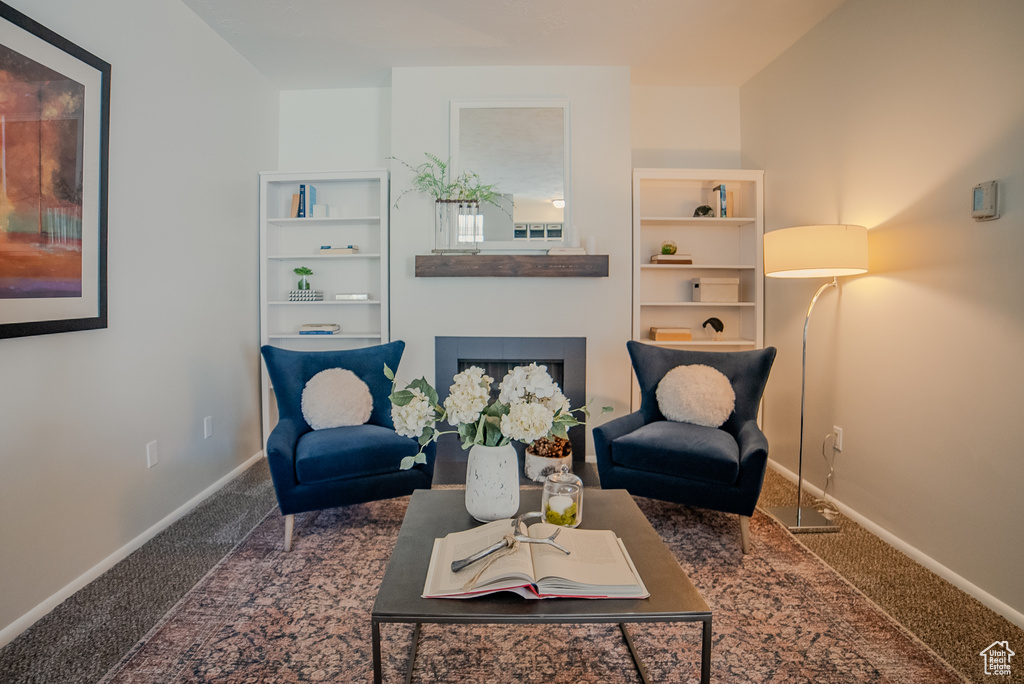 Living area with a fireplace and carpet flooring