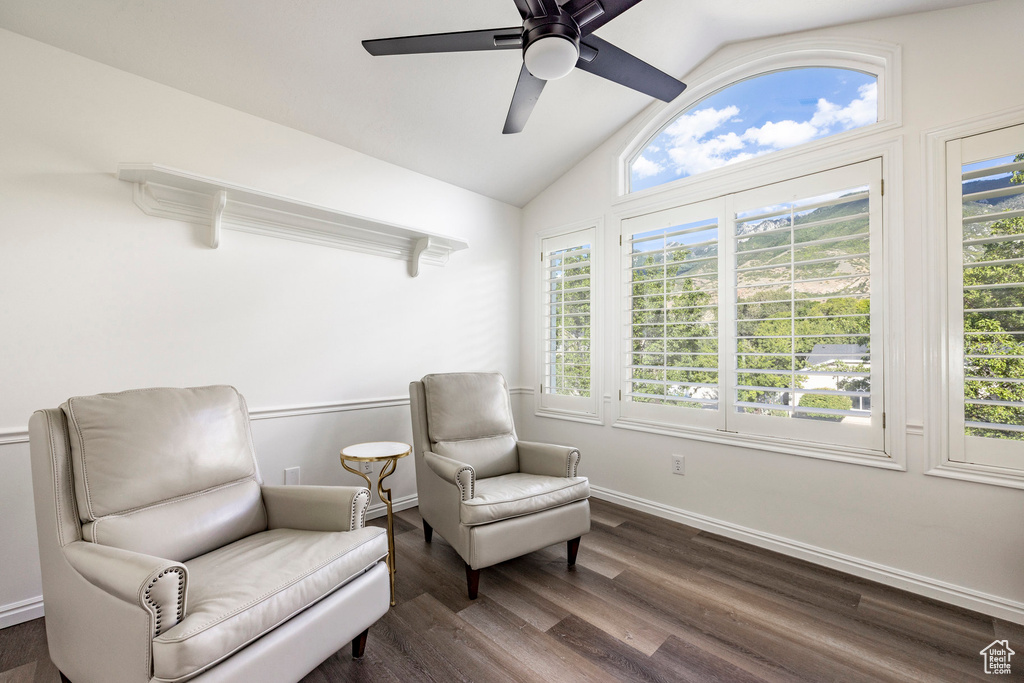 Living area with ceiling fan, vaulted ceiling, dark wood-type flooring, and a healthy amount of sunlight