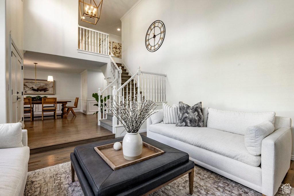 Living room featuring a towering ceiling, dark hardwood / wood-style floors, a chandelier, and ornamental molding