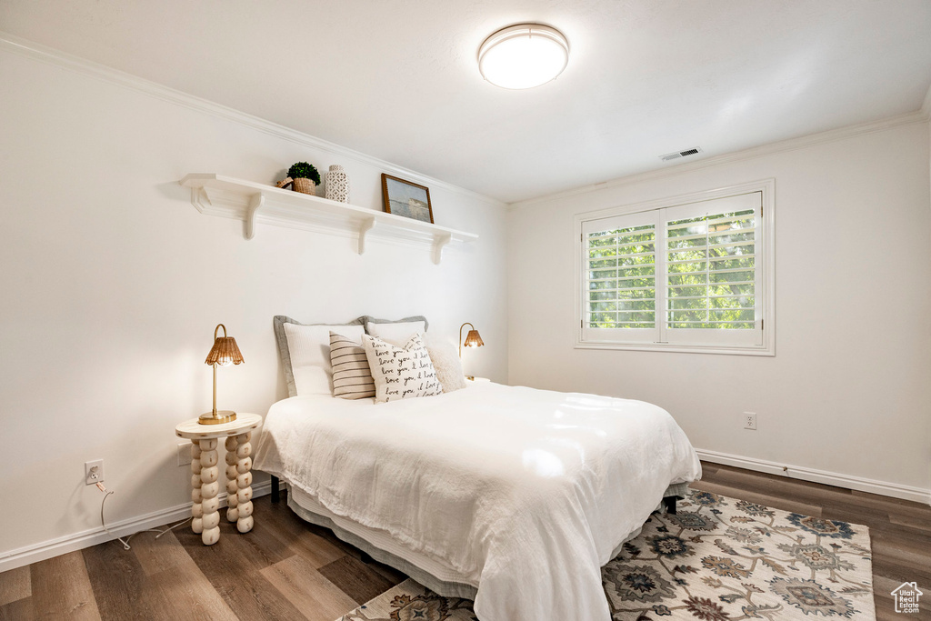 Bedroom with ornamental molding and dark hardwood / wood-style flooring