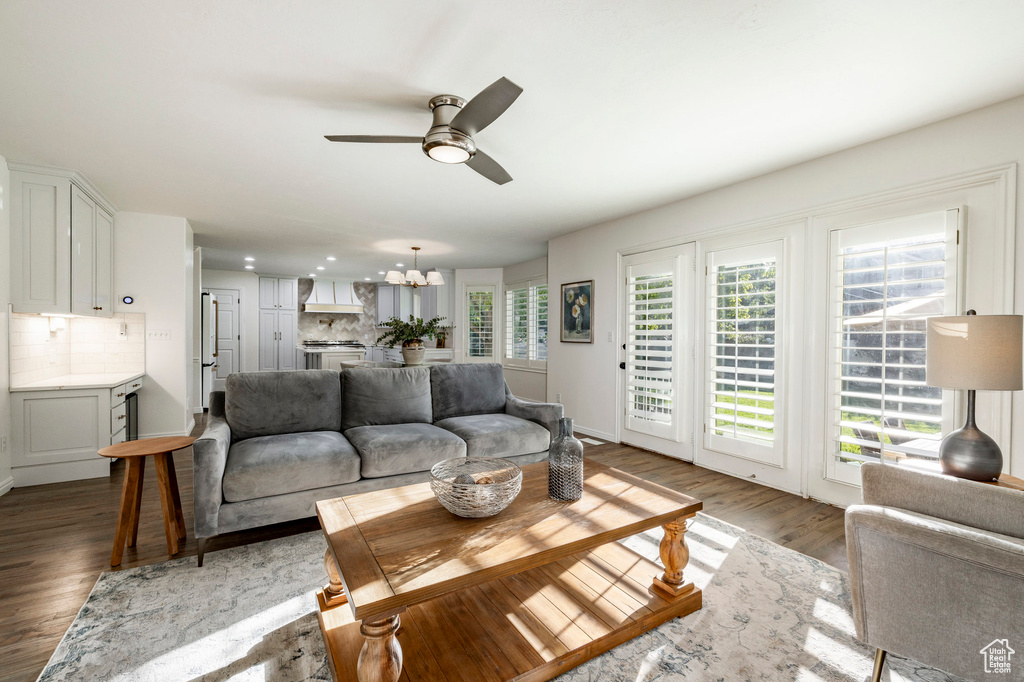 Living room with ceiling fan with notable chandelier, hardwood / wood-style flooring, and a healthy amount of sunlight