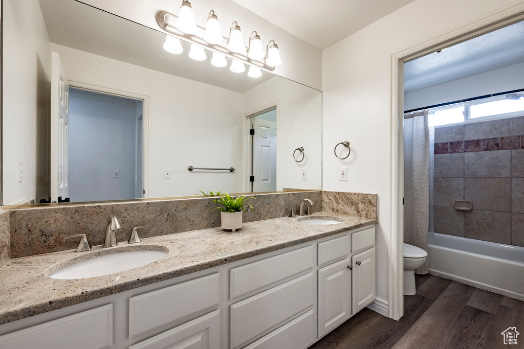 Full bathroom featuring toilet, vanity, hardwood / wood-style flooring, and shower / bathtub combination with curtain