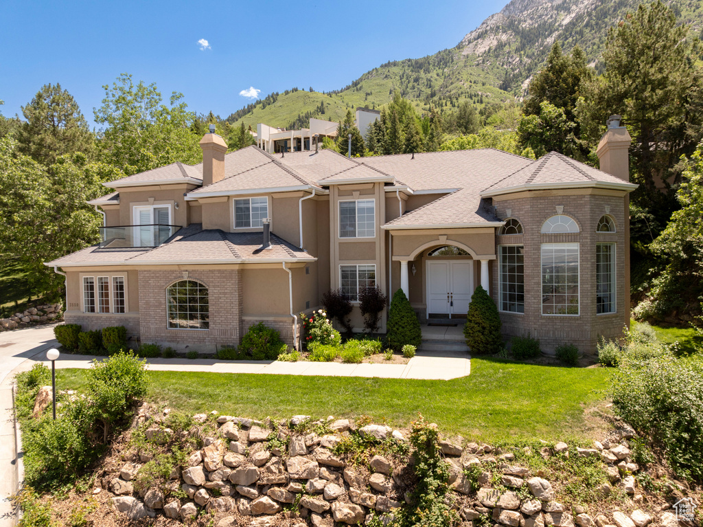 Mediterranean / spanish-style house with a chimney, a mountain view, a front yard, and stucco siding