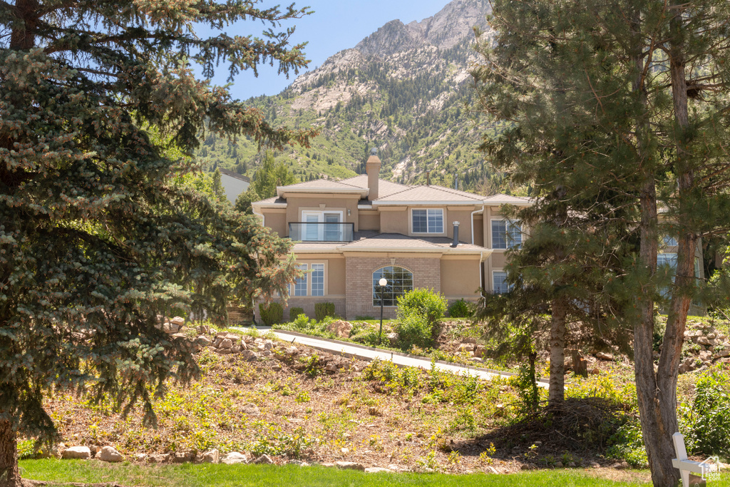 View of front of property featuring a chimney, a mountain view, and stucco siding