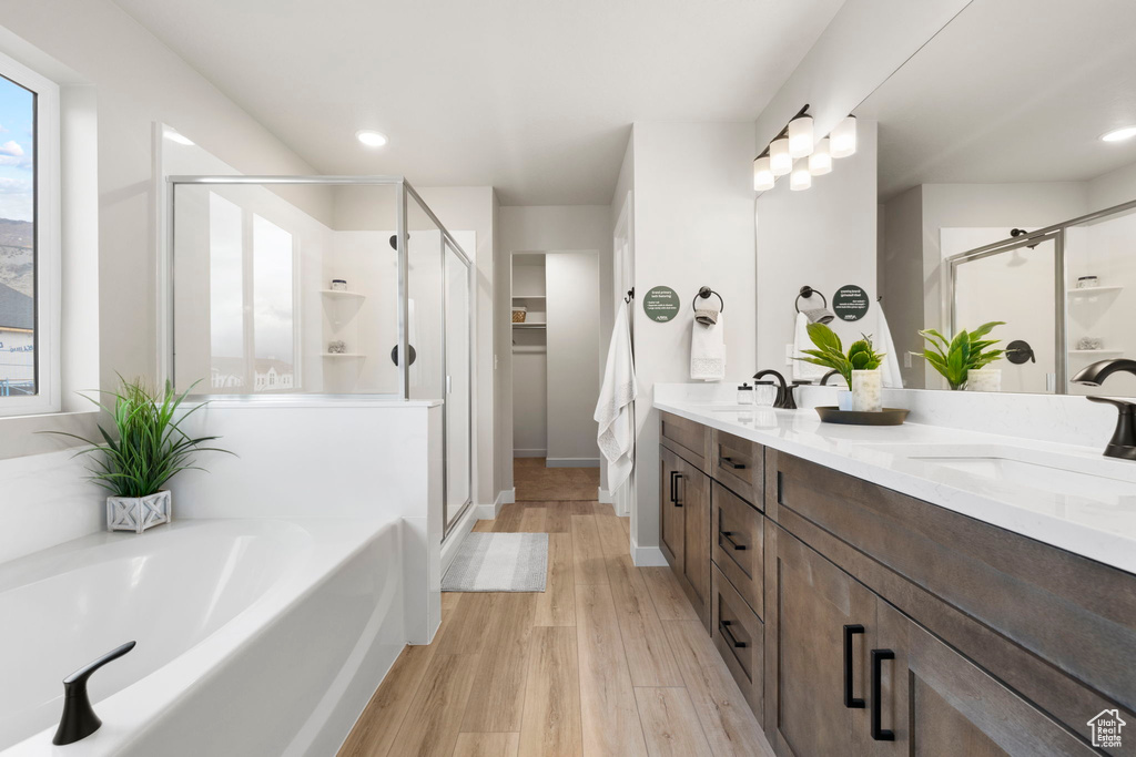 Bathroom with hardwood / wood-style flooring, independent shower and bath, and vanity