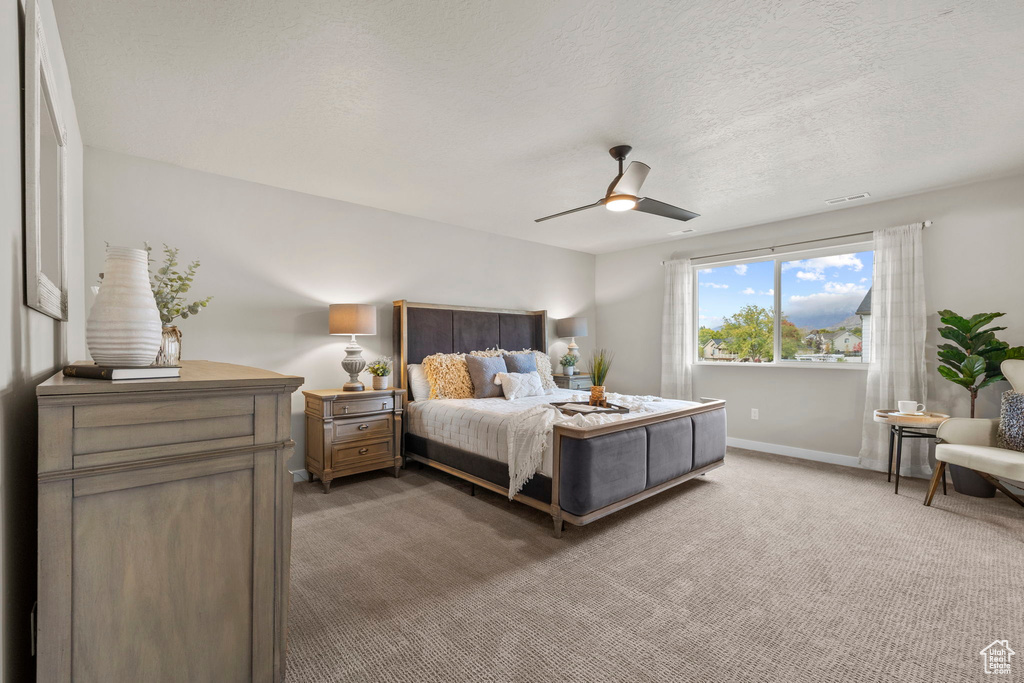 Bedroom featuring ceiling fan, carpet flooring, and a textured ceiling