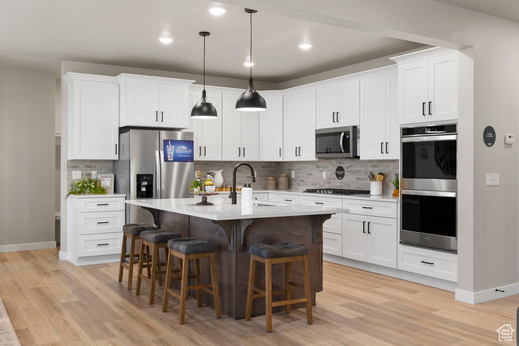 Kitchen with sink, tasteful backsplash, light hardwood / wood-style flooring, and stainless steel appliances