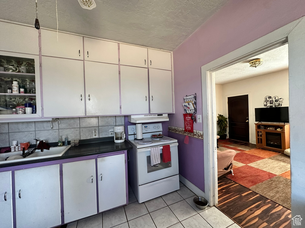 Kitchen with backsplash, light hardwood / wood-style flooring, white cabinetry, sink, and white electric stove