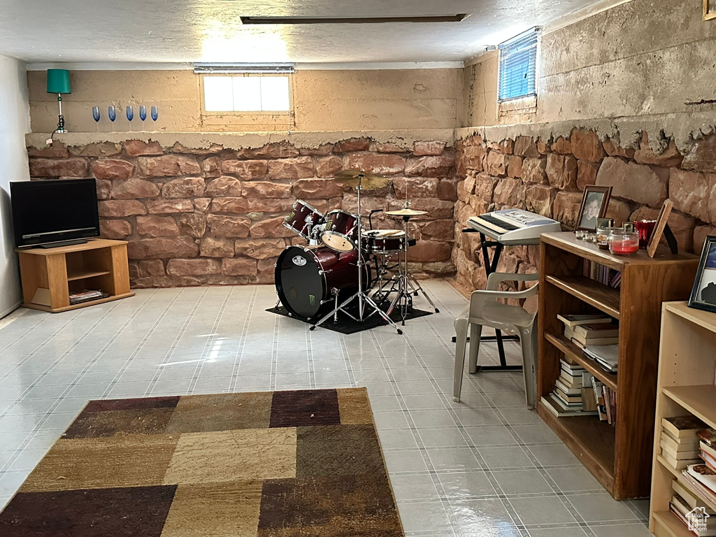 Basement featuring a textured ceiling, plenty of natural light, and light tile patterned flooring