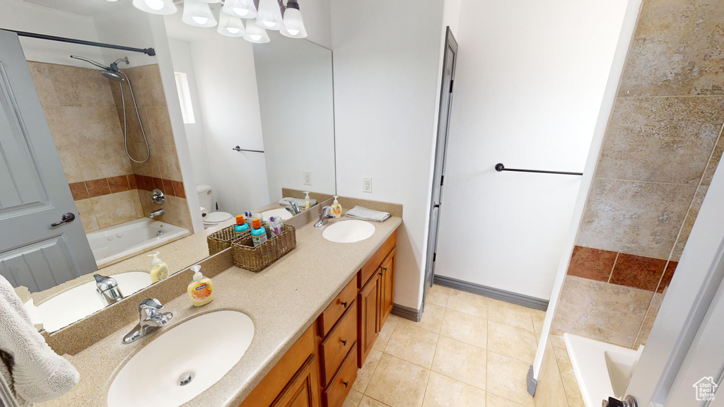 Full bathroom with toilet, tiled shower / bath, vanity, and tile patterned floors