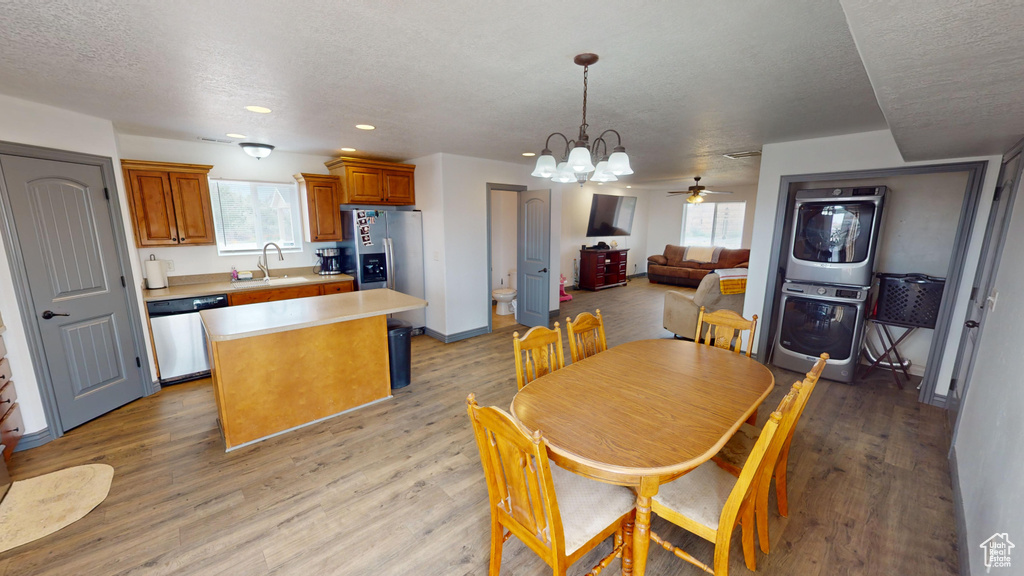 Dining room featuring light hardwood / wood-style floors, ceiling fan with notable chandelier, a textured ceiling, and a healthy amount of sunlight