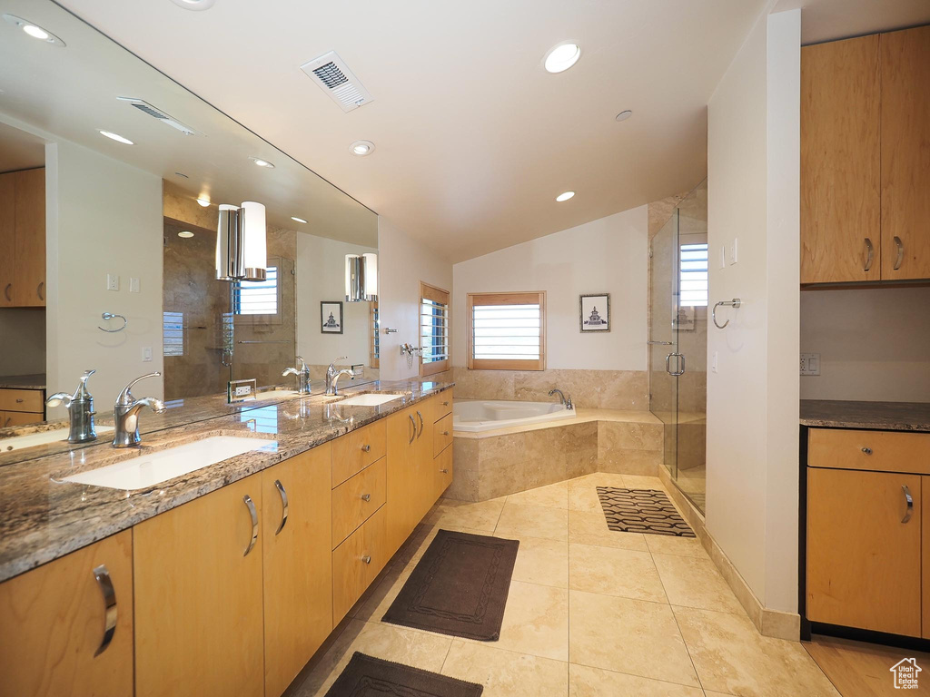 Bathroom with tile patterned flooring, lofted ceiling, separate shower and tub, and dual vanity