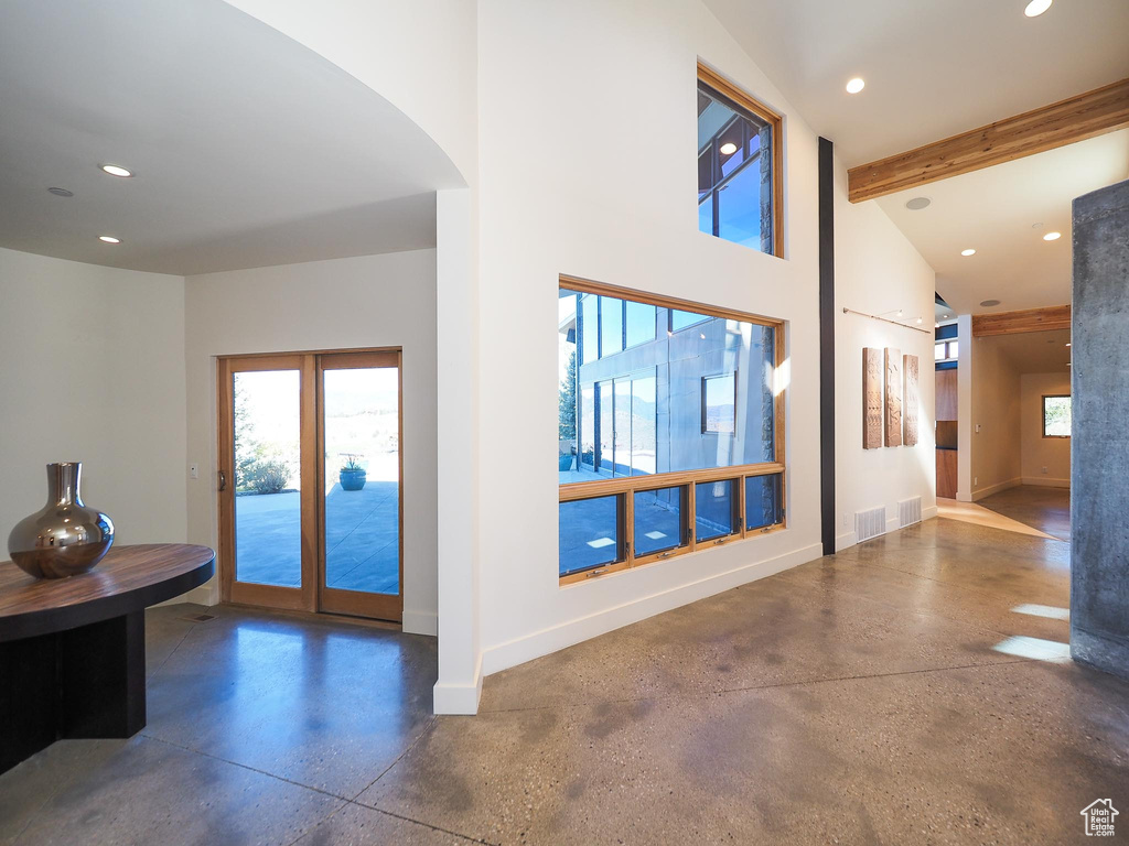 Interior space with vaulted ceiling with beams, concrete floors, and french doors