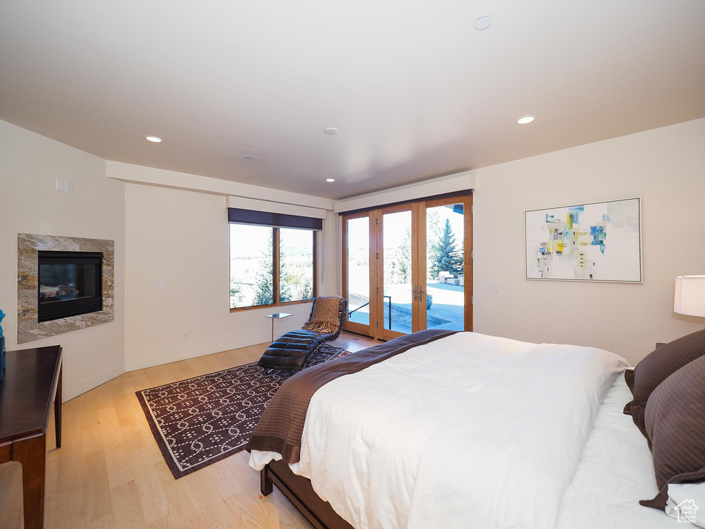 Bedroom featuring a fireplace, light hardwood / wood-style flooring, access to exterior, and french doors