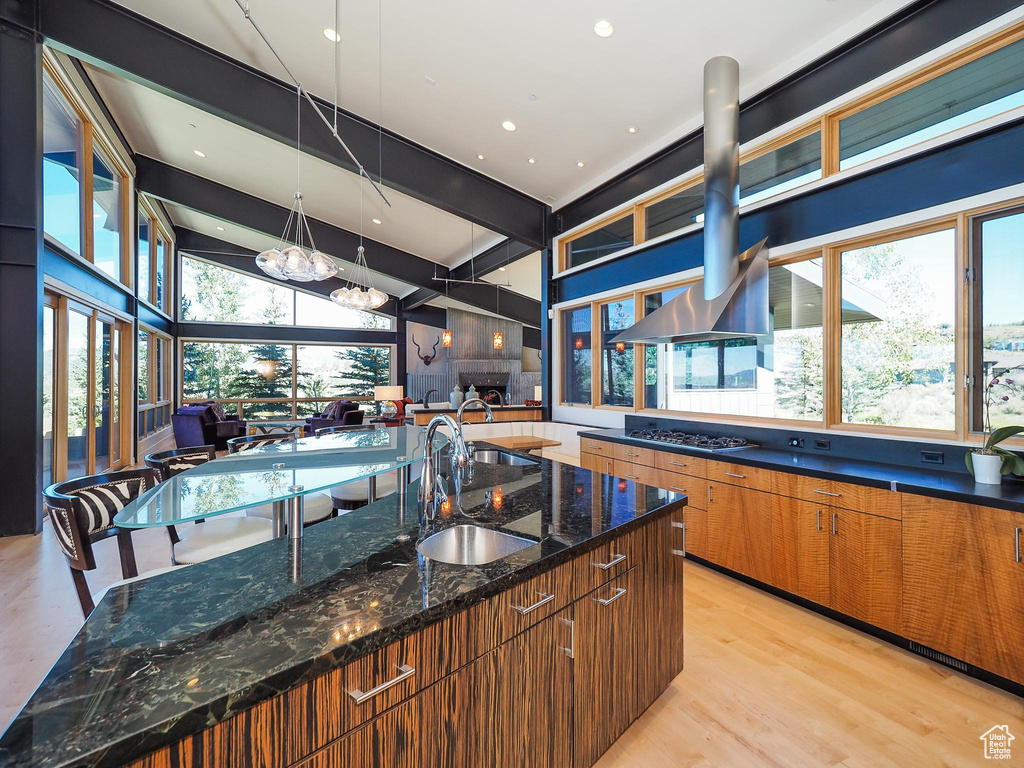 Kitchen featuring dark stone counters, vaulted ceiling with beams, plenty of natural light, and decorative light fixtures