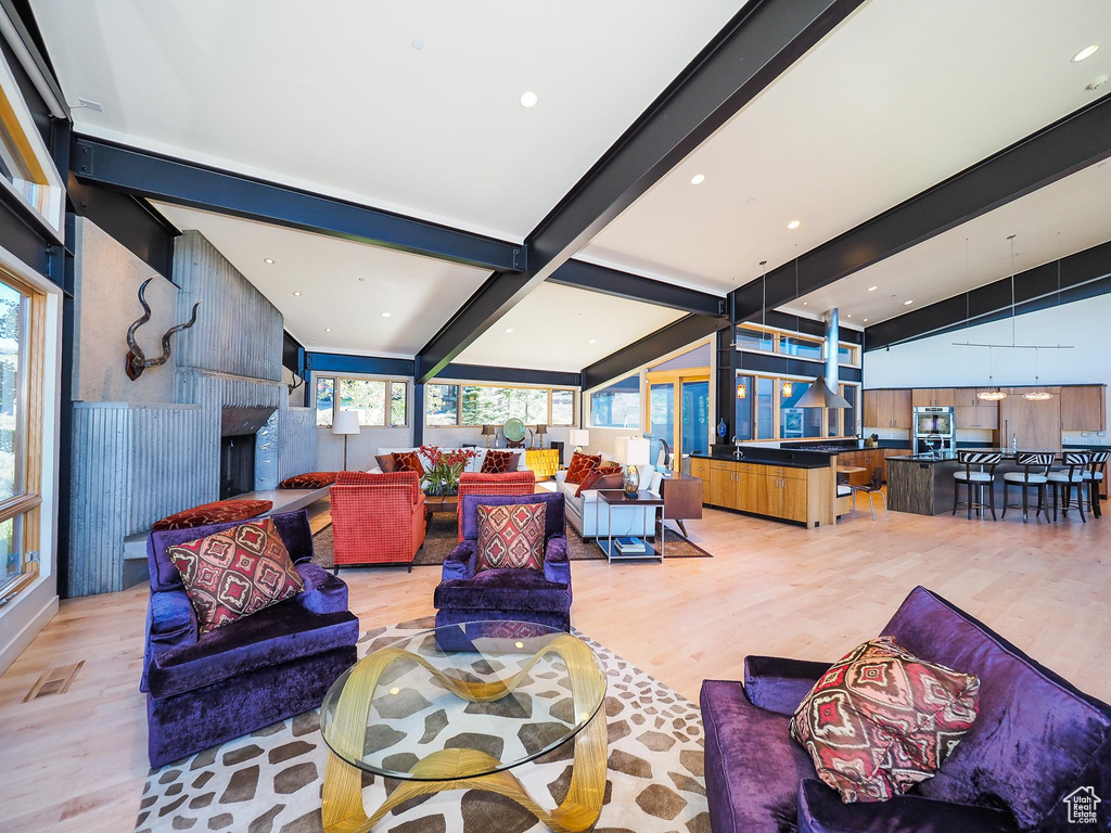 Living room with a wealth of natural light, light hardwood / wood-style floors, and lofted ceiling with beams