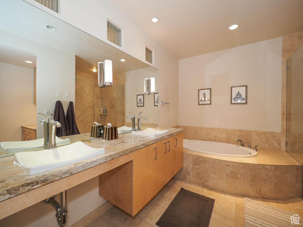 Bathroom with tile patterned flooring, separate shower and tub, and dual vanity