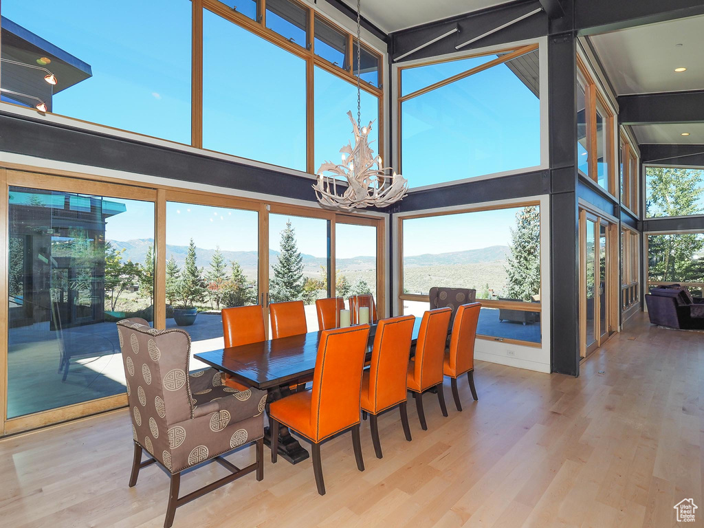 Dining room featuring a mountain view, a towering ceiling, an inviting chandelier, and light hardwood / wood-style flooring