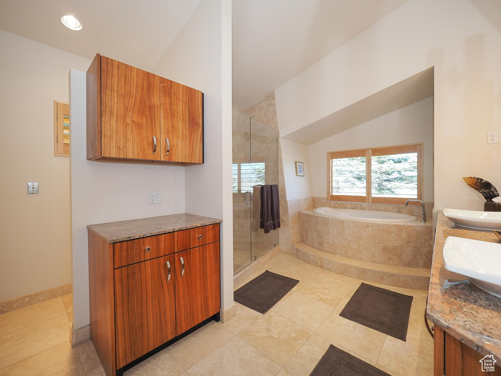 Bathroom with tile patterned floors, vaulted ceiling, and vanity