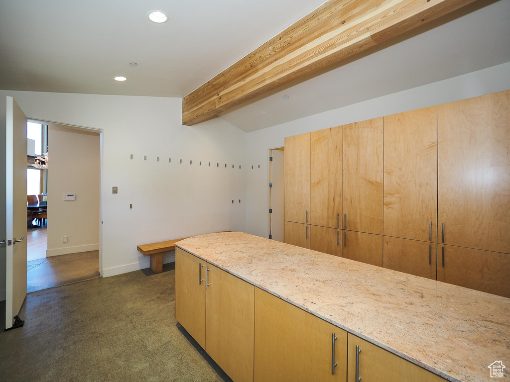 Kitchen featuring lofted ceiling with beams, light stone counters, and light brown cabinetry