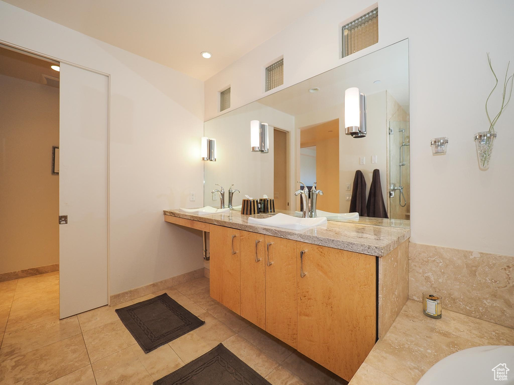 Bathroom featuring dual vanity, walk in shower, and tile patterned floors