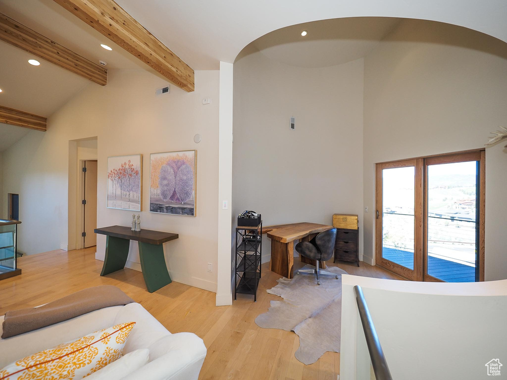 Office area with light hardwood / wood-style floors and beamed ceiling