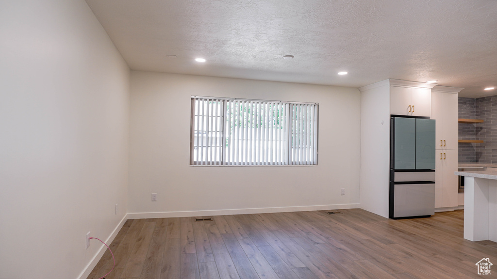 Spare room featuring light wood-type flooring and a textured ceiling