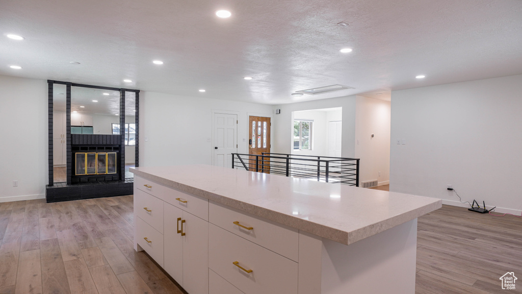 Kitchen with white cabinets, light wood-type flooring, and a kitchen island