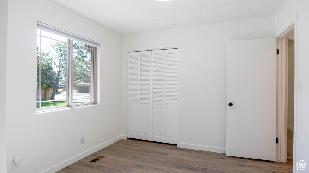 Unfurnished bedroom featuring light hardwood / wood-style flooring, a closet, and multiple windows