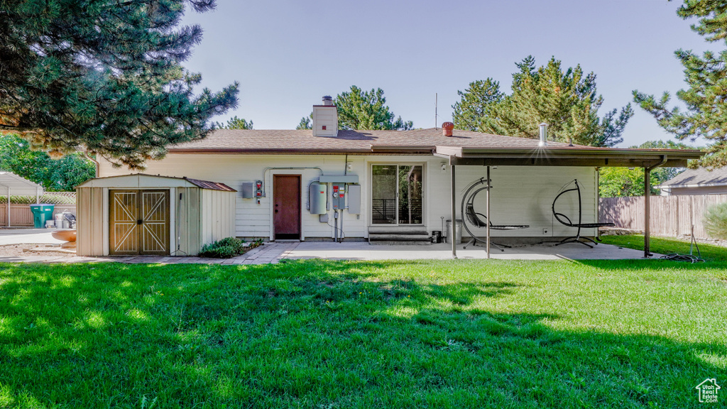 Back of house with a lawn, a patio, and a shed