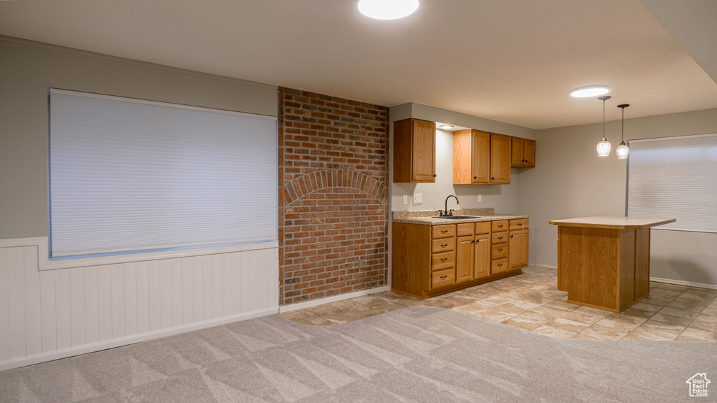 Kitchen with sink, a center island, light colored carpet, and hanging light fixtures