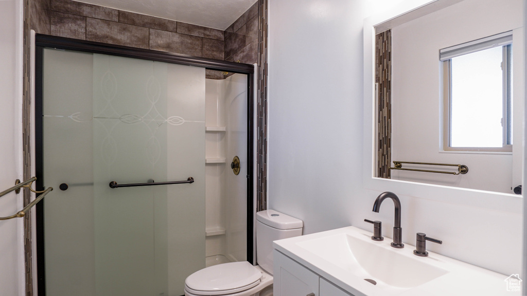 Bathroom with an enclosed shower, vanity, and toilet