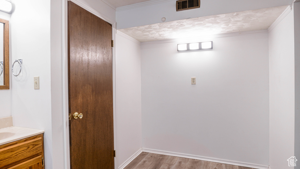 Bathroom featuring hardwood / wood-style floors, ornamental molding, and vanity