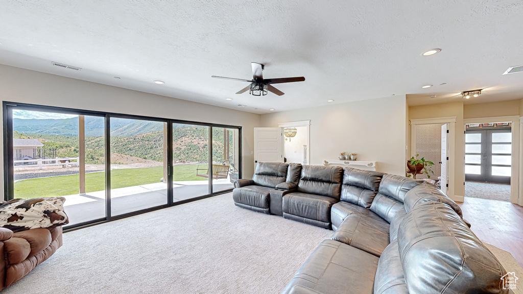 Carpeted living room featuring ceiling fan and french doors