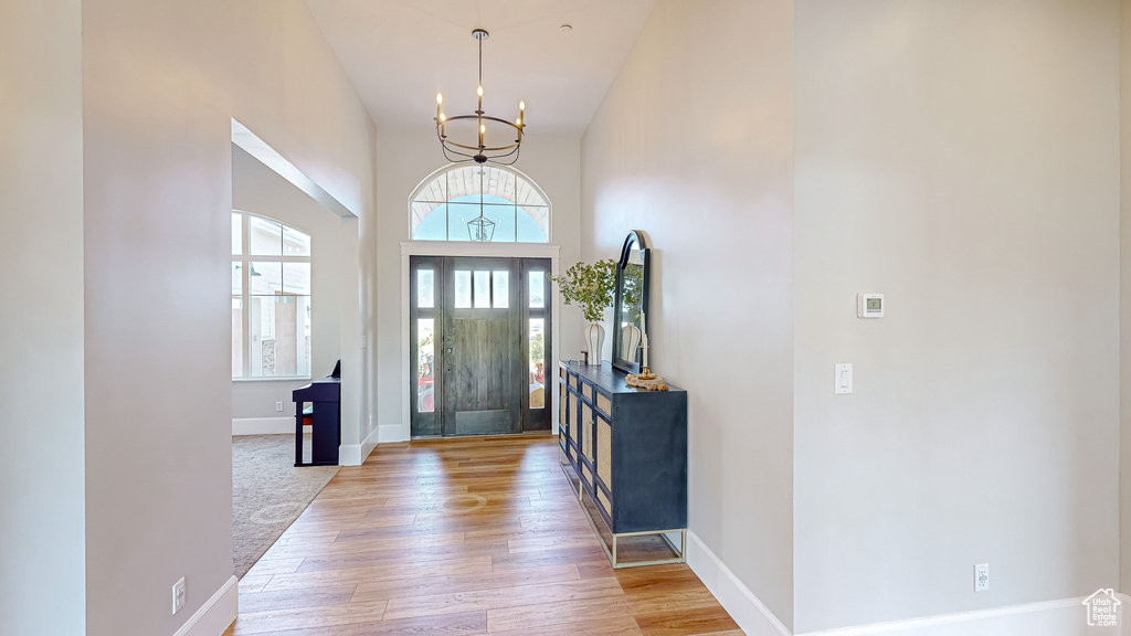 Foyer entrance featuring light colored carpet, a notable chandelier, and a high ceiling