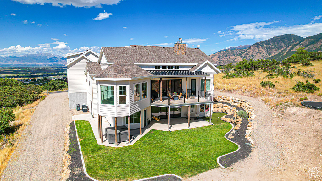 Back of property with a mountain view, a patio area, and a yard