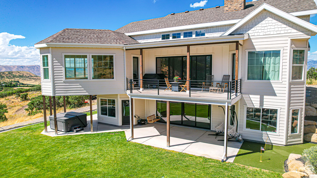 Rear view of property with a patio area, a balcony, and a lawn