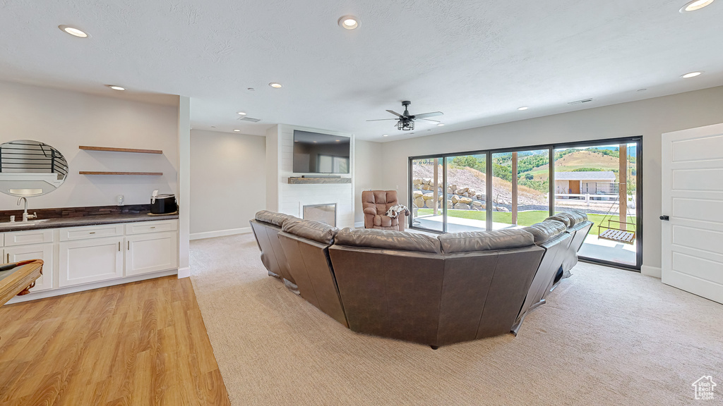 Living room featuring sink, a fireplace, light hardwood / wood-style flooring, and ceiling fan