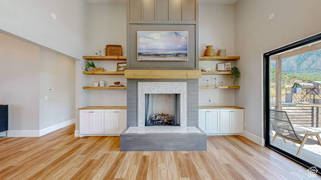 Unfurnished living room featuring light wood-type flooring and a high ceiling