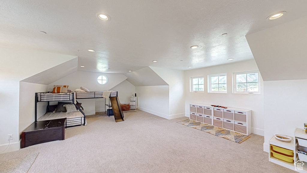 Additional living space with light colored carpet and lofted ceiling