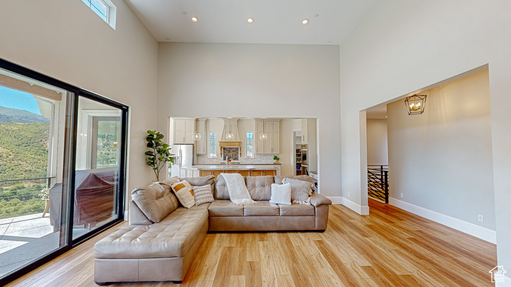 Living room with light hardwood / wood-style floors, a healthy amount of sunlight, and a high ceiling