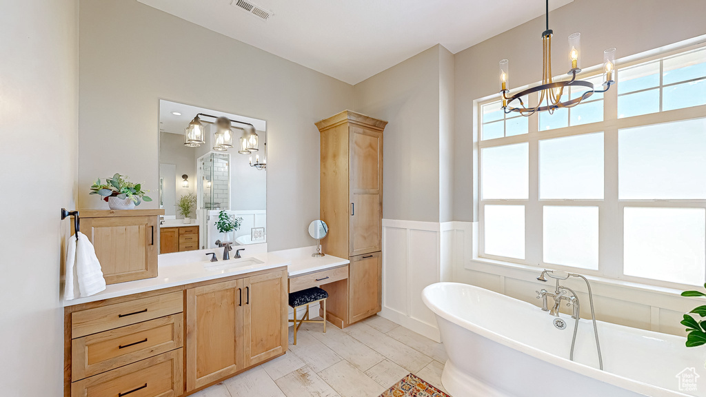 Bathroom with tile patterned flooring, an inviting chandelier, a tub, and vanity